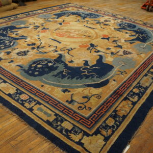 Gold rug with a navy blue and light blue medallion and dragon motifs, displayed on hardwood flooring.