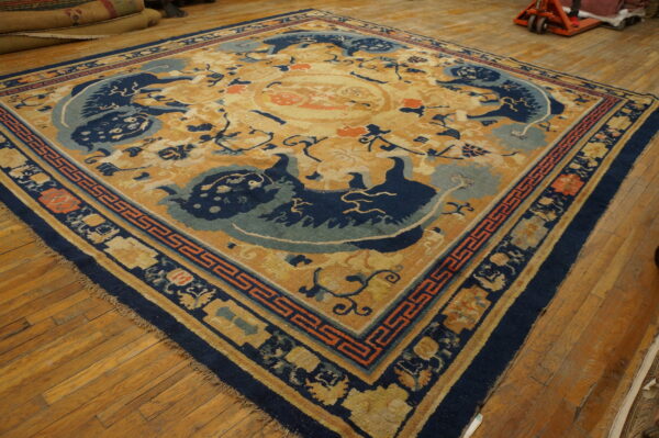 Gold rug with a navy blue and light blue medallion and dragon motifs, displayed on hardwood flooring.