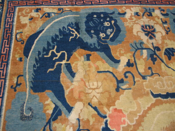 Close view of a rug with a dark blue animal pattern set against an orange, cream, and coral floral field.