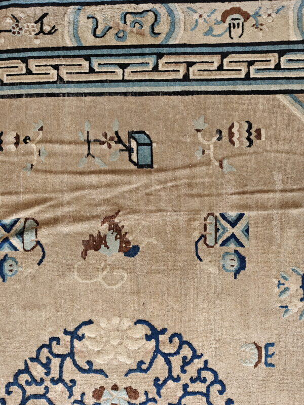 Beige rug detail shows a dark blue geometric border and tan field with scattered blue and brown designs.