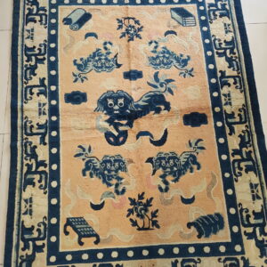 Navy blue and tan rug with stylized animal motifs and multiple ornate borders on a white tiled floor.