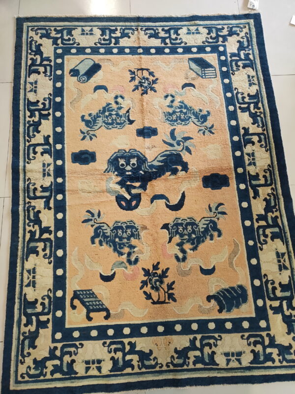 Navy blue and tan rug with stylized animal motifs and multiple ornate borders on a white tiled floor.