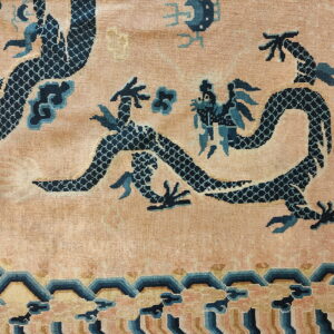 Low-pile peach rug featuring dark blue serpentine dragons and a tiered wave border.