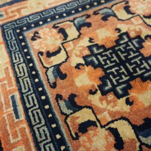 High-pile rug featuring rust, navy, and tan geometric patterns shown against wood flooring.