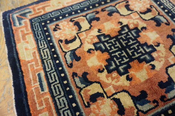 High-pile rug featuring rust, navy, and tan geometric patterns shown against wood flooring.