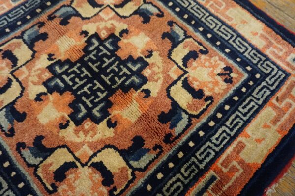Navy, terracotta, and tan rug detail showing a complex geometric pattern and an intricate meander border.