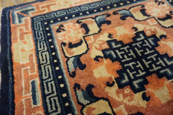 Close-up of a rug featuring deep blue, terracotta, and beige geometric patterns with a visible medium pile.