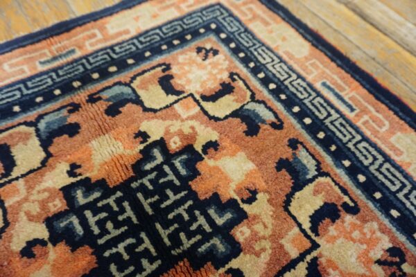 Textured rug detail showing navy, rust, and cream patterns over distressed wood flooring.
