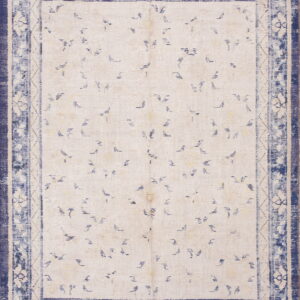 Distressed cream and indigo rug with scattered minimalist dash patterns and wide floral and geometric borders.