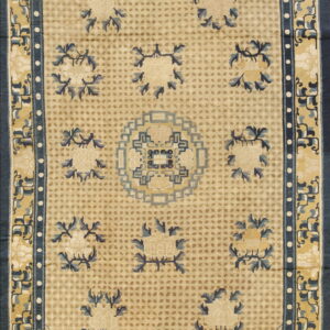 Beige rug with a dotted field, stylized blue floral clusters, and intricate geometric Greek key borders.
