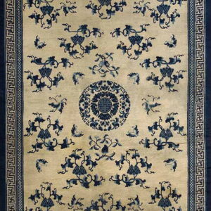 Cream and indigo rug featuring a dense floral vine pattern, central medallion, and geometric border.