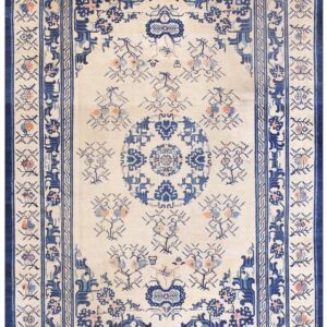 Ivory rug with complex navy blue borders, a central medallion, and scattered floral motifs in blue and coral.