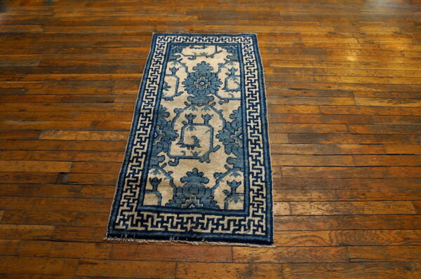 A blue and tan patterned accent rug sits centered on rustic, wide plank hardwood floors.