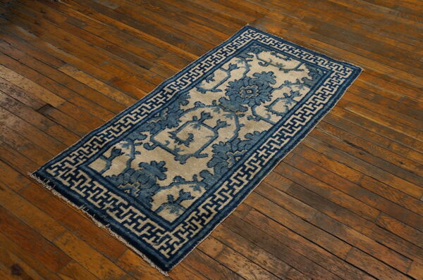 Blue and beige runner rug featuring floral and geometric patterns on rustic wood flooring.
