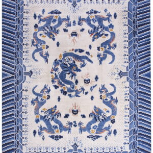 Overhead view of a white rug patterned with stylized blue dragons and a wide blue geometric border.