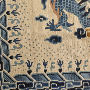 Stylized blue dragon and cloud motifs are featured on a beige rug with an ornate blue geometric border.
