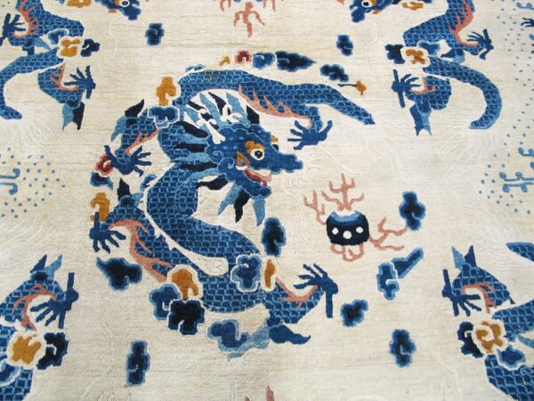 Close-up of a pale ivory rug featuring a stylized blue dragon motif accented with rust and gold.