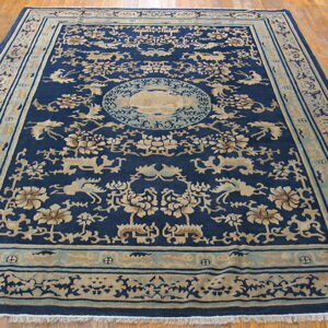 Navy blue rug with tan floral and animal motifs, plus a central medallion, rests on wood flooring.
