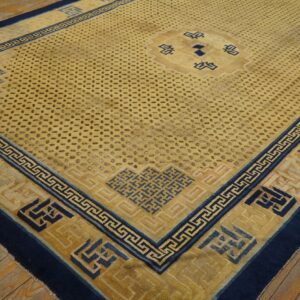Yellow and navy geometric rug featuring a field of dark subtle motifs on distressed wooden flooring.
