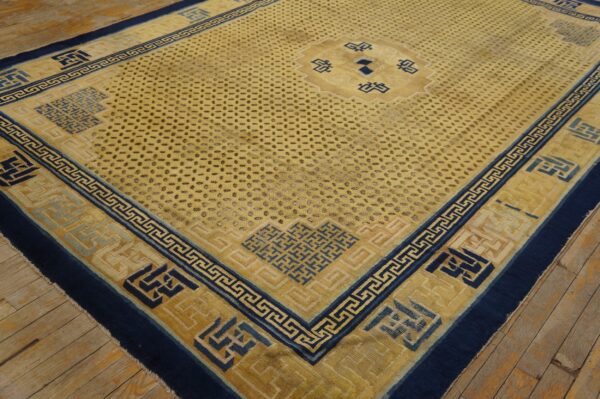 Yellow and navy geometric rug featuring a field of dark subtle motifs on distressed wooden flooring.