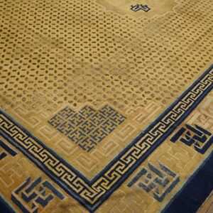 Yellow rug featuring navy blue fretwork borders and a repeating dotted field pattern lies on wooden plank flooring.