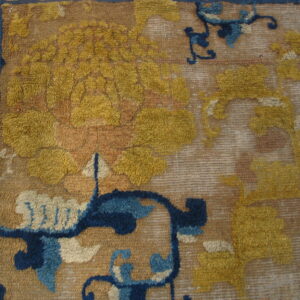 Textured rug detail shows yellow and blue floral motifs on a tan ground beside wood flooring.