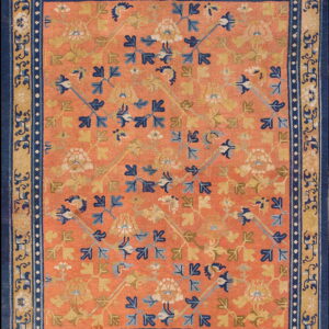 An orange rug with scattered blue and gold stylized floral motifs and a multi-layered navy and gold border.