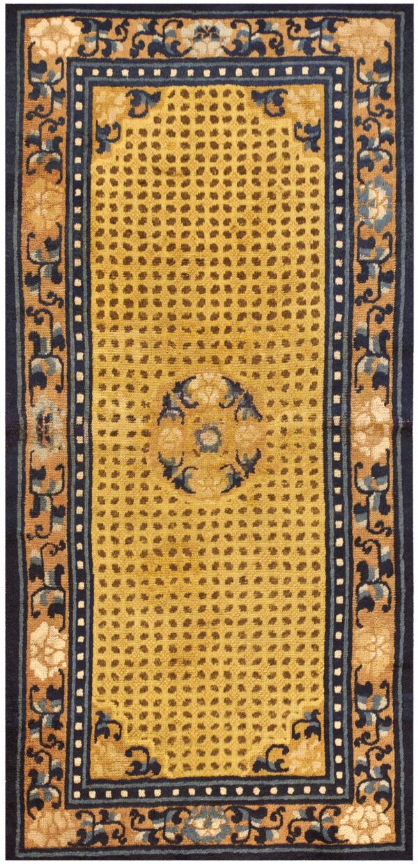 A rectangular rug with a mustard yellow dotted field and dark navy floral borders on a tan ground.