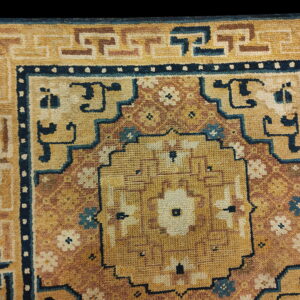 Golden yellow rug with a terracotta field, dark blue accents, and a complex geometric border pattern.