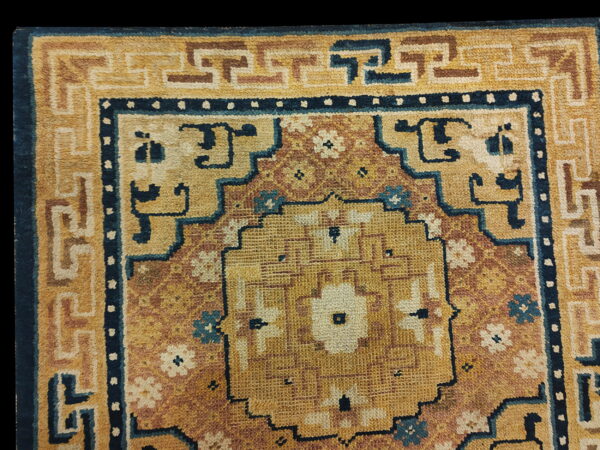 Golden yellow rug with a terracotta field, dark blue accents, and a complex geometric border pattern.