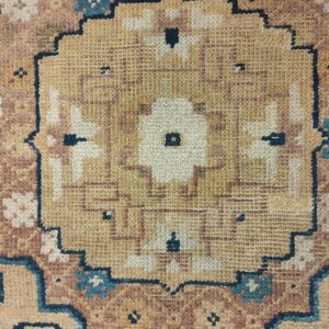 Tan, dusty rose, and cream rug detail with a central medallion and dark blue geometric outlining.