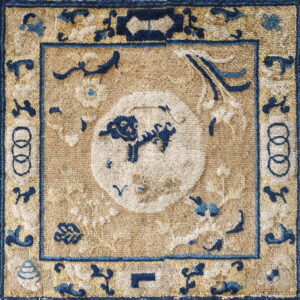 Small, textural rug featuring a blue animal design inside a white circle on a distressed tan field.