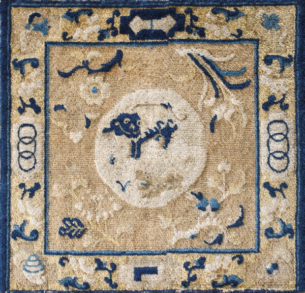 Small, textural rug featuring a blue animal design inside a white circle on a distressed tan field.