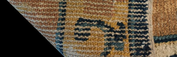 Detailed close-up of a chunky textured rug in horizontal bands of rust, yellow, cream, navy, and teal.