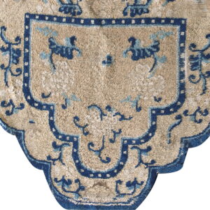 Tan rug detail with dark blue stepped border and stylized light blue and navy motifs.