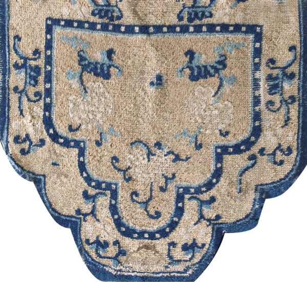 Tan rug detail with dark blue stepped border and stylized light blue and navy motifs.