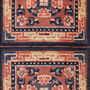 High-pile rug detail with repeating terracotta and navy panels surrounded by geometric borders.
