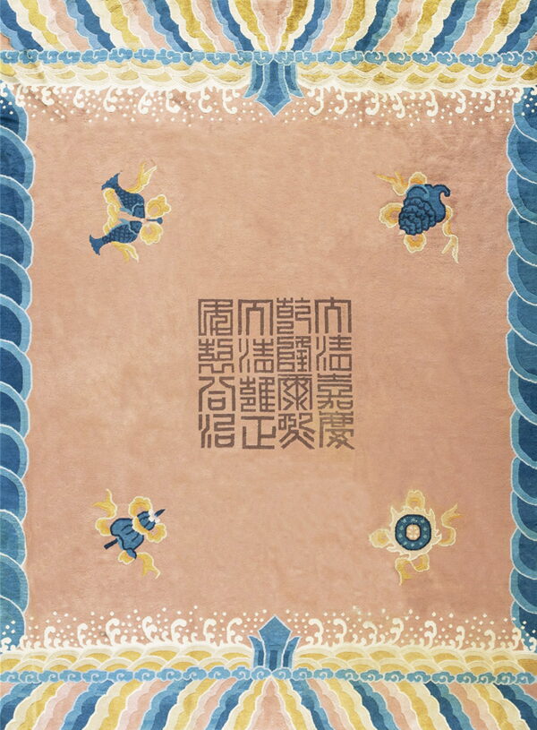 Ornate pink rug with blue and yellow wave borders, stylized corner figures, and brown central script.