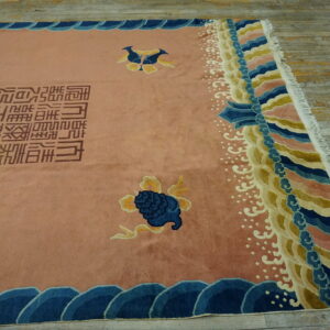 Pink rug featuring blue and yellow motifs, brown script, and multi-colored scalloped borders on worn wood planks.
