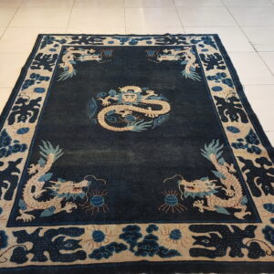 Rectangular dark blue rug featuring beige and pale blue dragons on light tiled floor.