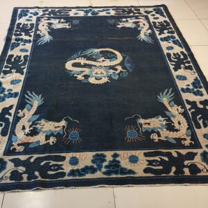 Indigo field rug with white and pale blue dragons and border patterns on beige tiled flooring.