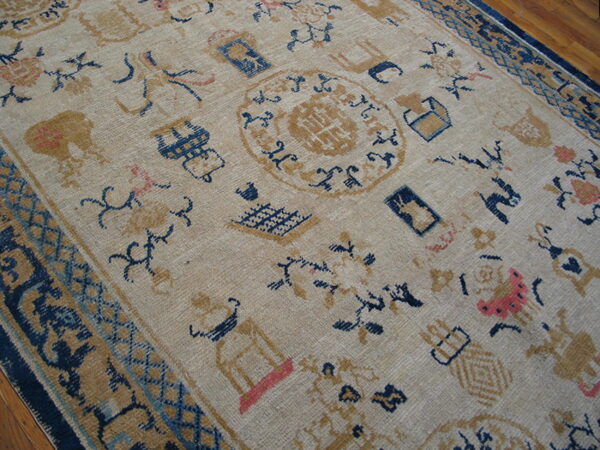 Low-pile rug in beige, navy, and gold scattered with symbols, resting on a brown hardwood floor.