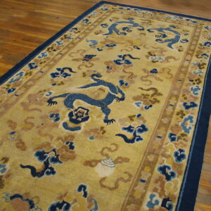 Long, low-pile rug with blue dragon and cloud motifs on a gold field, placed on wood flooring.