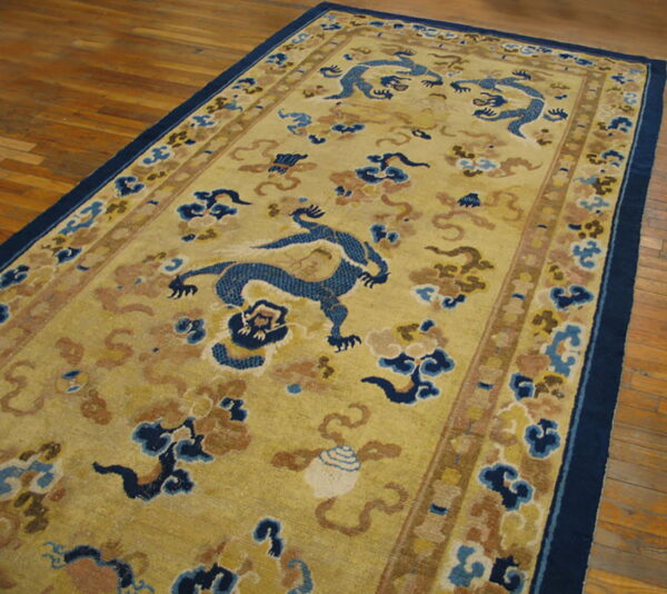 Long, low-pile rug with blue dragon and cloud motifs on a gold field, placed on wood flooring.