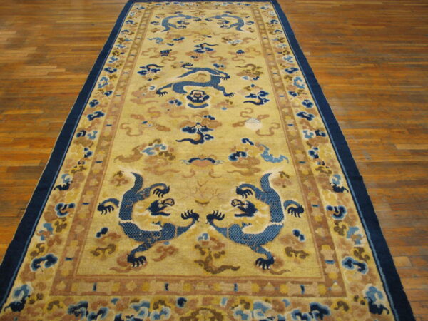 Mustard yellow runner rug featuring dark blue dragons and cloud patterns on hardwood planks.