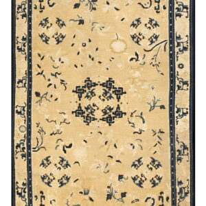 Tan rug with low pile features a repeating navy blue floral and geometric pattern.