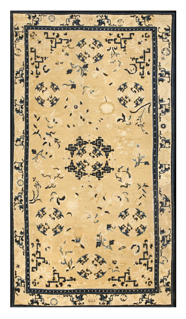 Tan rug with low pile features a repeating navy blue floral and geometric pattern.