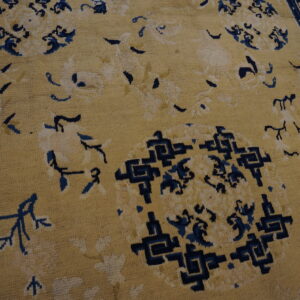 Tan rug with dark blue florals and central geometric patterns visible on a wood floor.