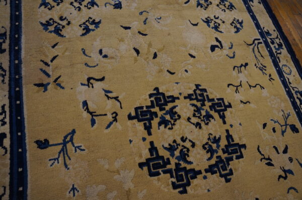 Tan rug with dark blue florals and central geometric patterns visible on a wood floor.
