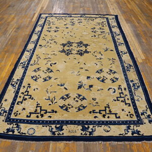 Yellow rug featuring a bold navy blue Oriental pattern and large geometric border on hardwood flooring.